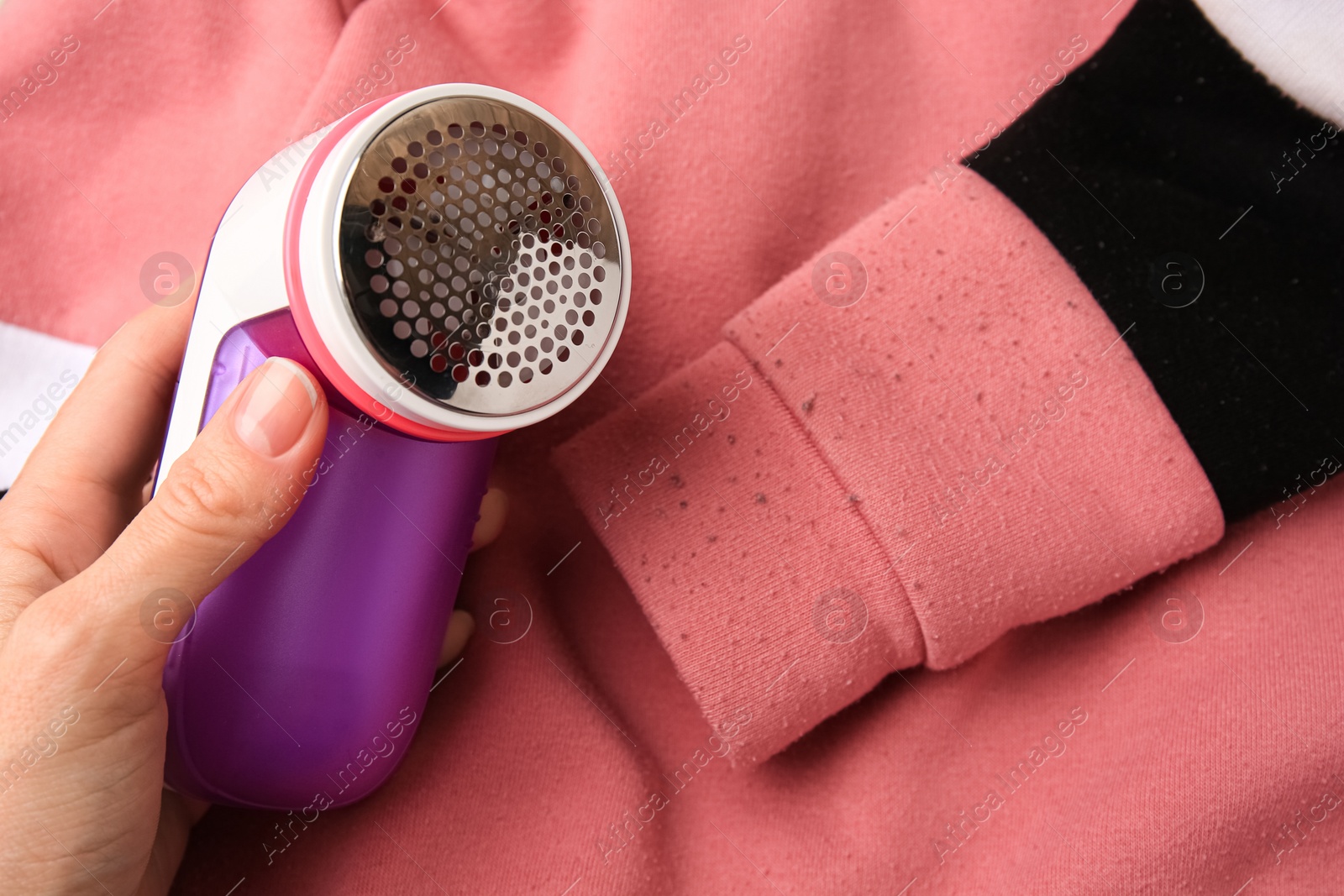 Photo of Woman holding fabric shaver near sweater with lint, closeup