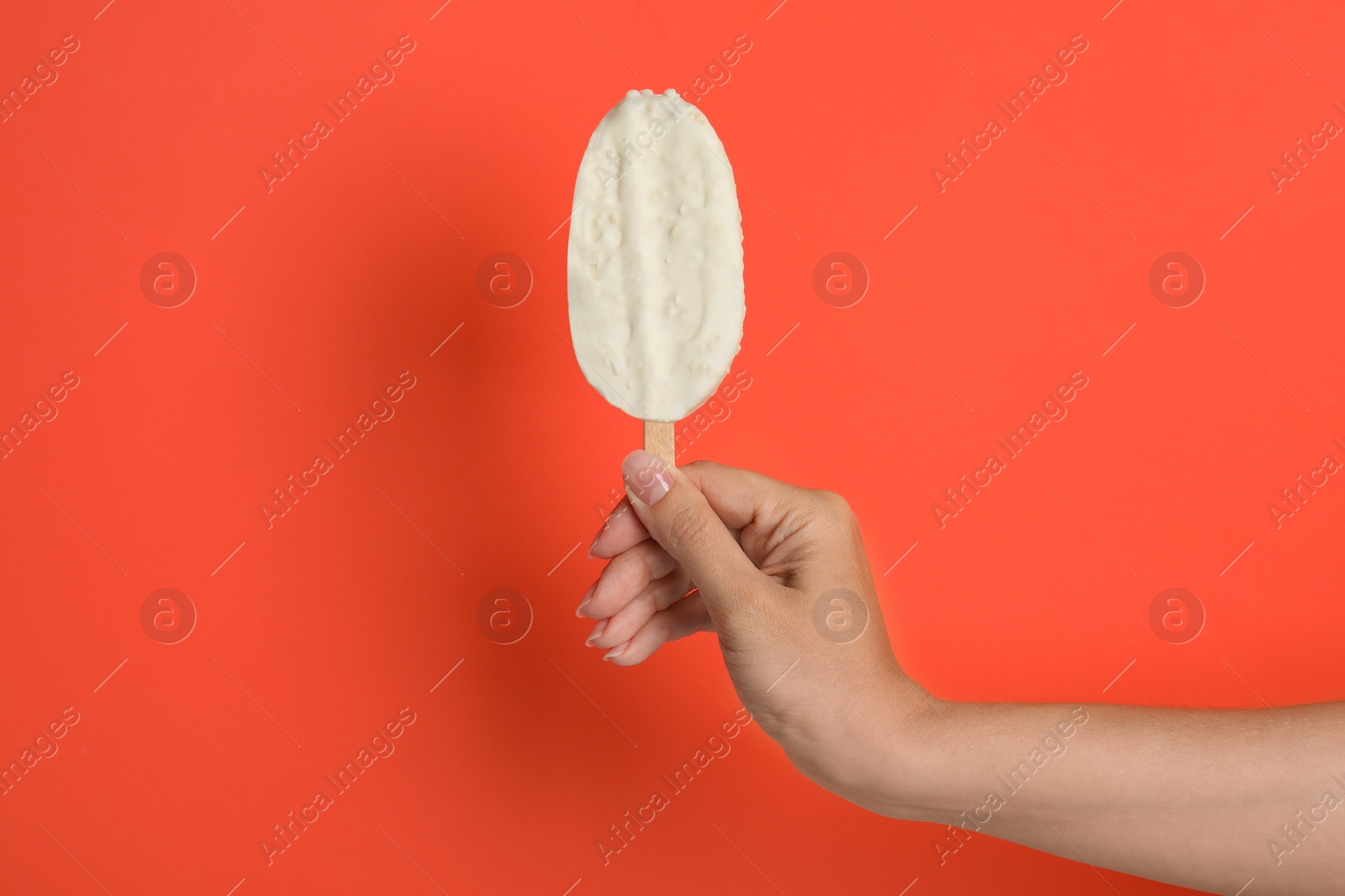 Photo of Woman holding ice cream with glaze on red background, closeup