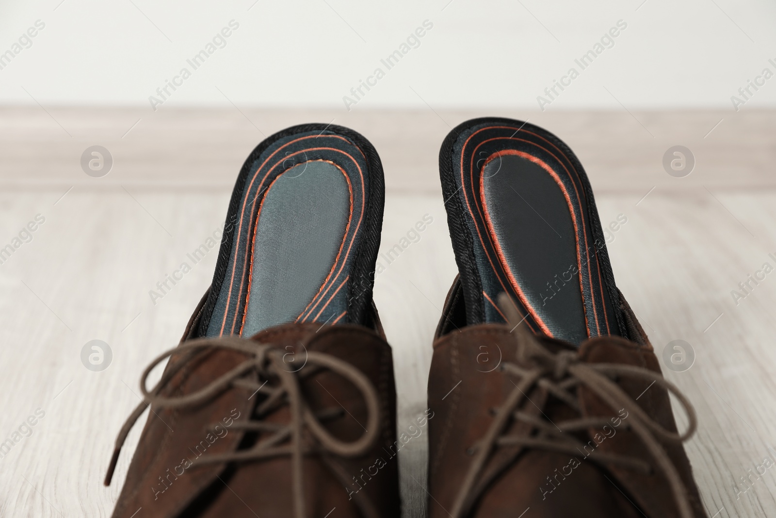 Photo of Orthopedic insoles in shoes on floor, closeup