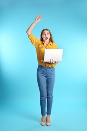 Photo of Emotional young woman with laptop celebrating victory on color background