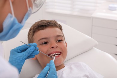 Photo of Dentist examining little boy's teeth in modern clinic