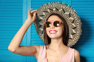 Photo of Beautiful woman wearing sunglasses and hat near blue wooden folding screen