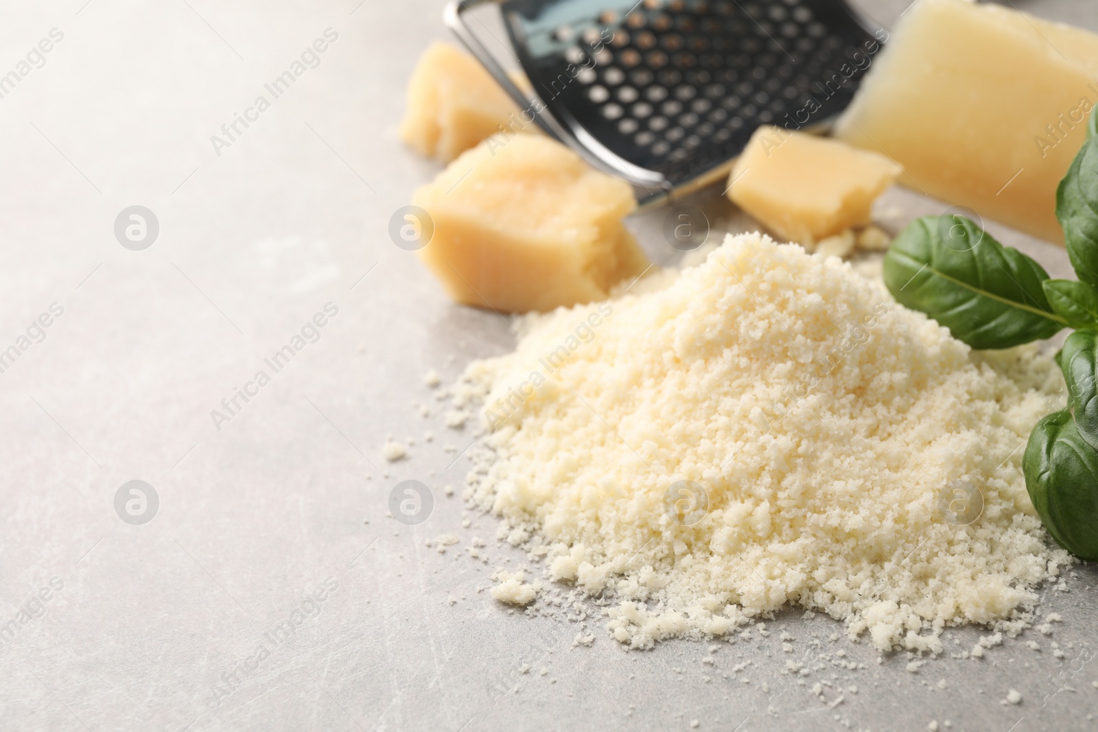 Photo of Pile of grated parmesan cheese on light table, closeup. Space for text