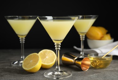 Photo of Delicious bee's knees cocktails and ingredients on grey table against black background