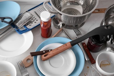 Many dirty utensils and dishware on countertop in messy kitchen, above view