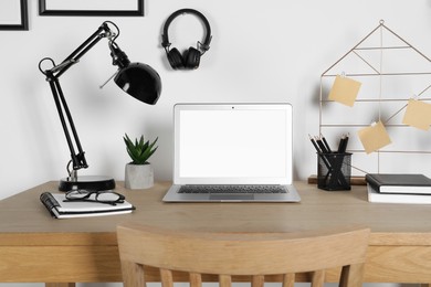 Photo of Home workplace. Laptop, lamp and stationery on wooden desk