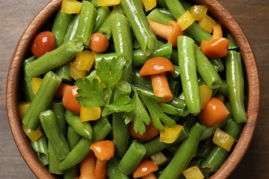 Photo of Bowl of tasty salad with green beans on wooden table, top view
