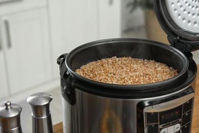 Photo of Modern multi cooker with delicious hot buckwheat in kitchen. Space for text