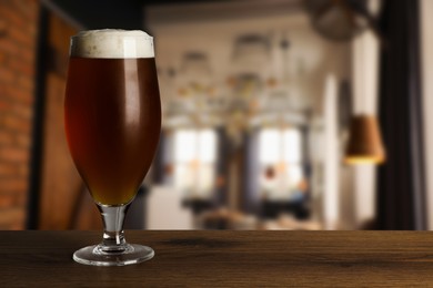 Image of Glass with fresh beer on wooden table in pub, space for text