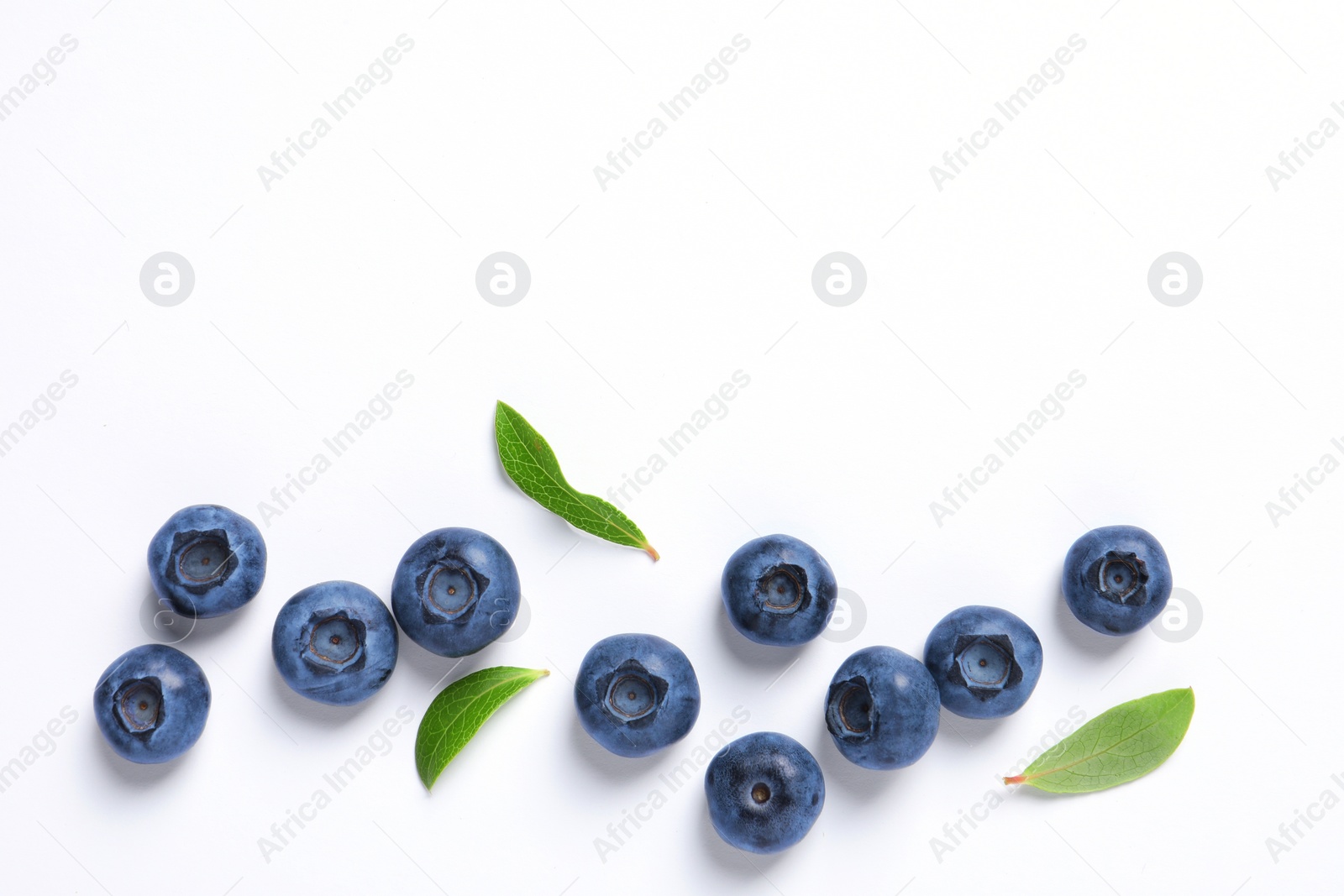 Photo of Tasty fresh blueberries with green leaves on white background, flat lay. Space for text