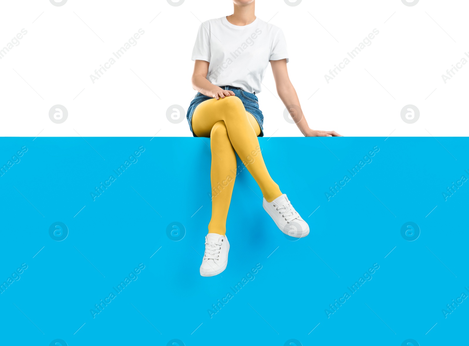 Photo of Woman wearing yellow tights and stylish shoes sitting on color background, closeup