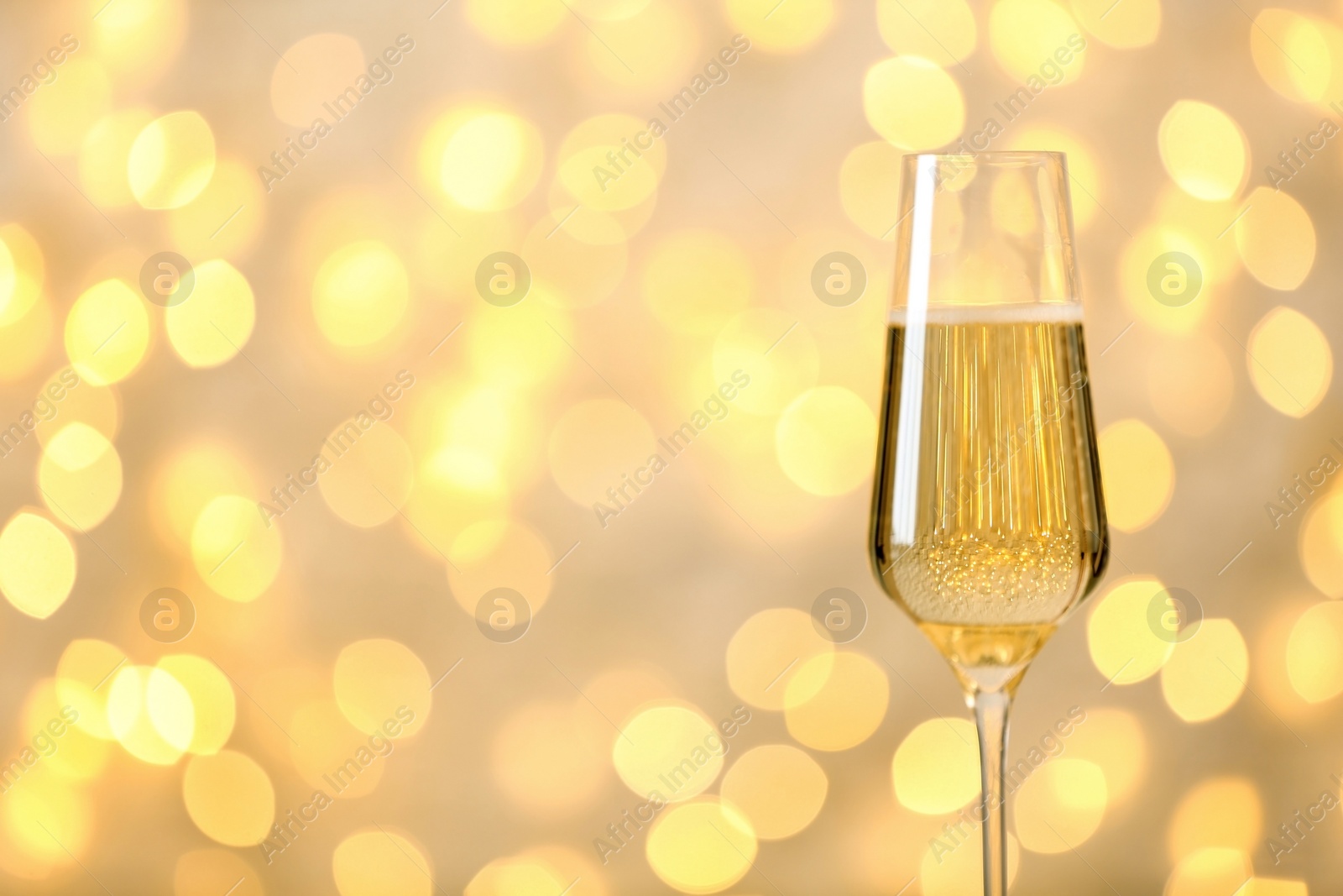 Photo of Glass of champagne against blurred lights. Space for text