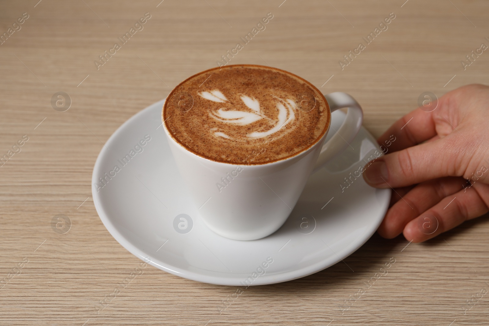 Photo of Woman with cup of aromatic coffee at wooden table, closeup