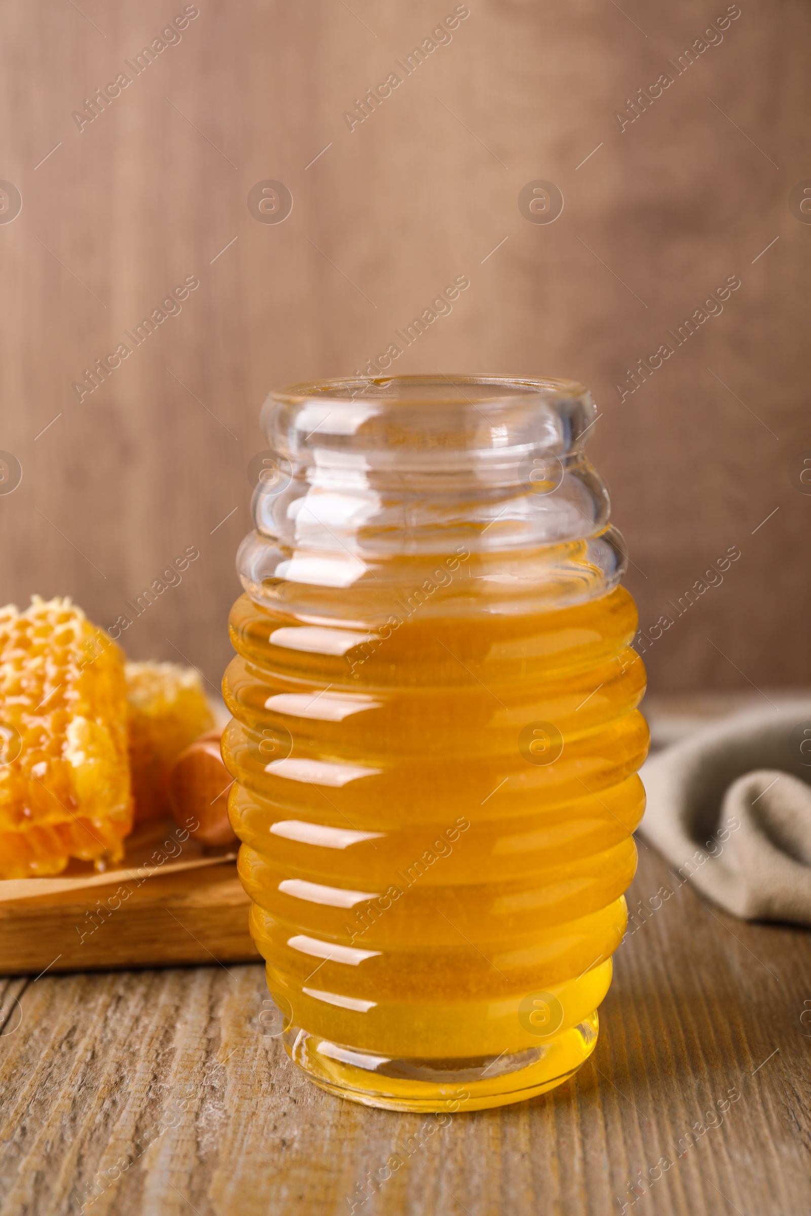 Photo of Jar of tasty aromatic honey on wooden table