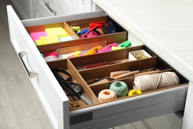 Sewing accessories and stationery in open desk drawer indoors