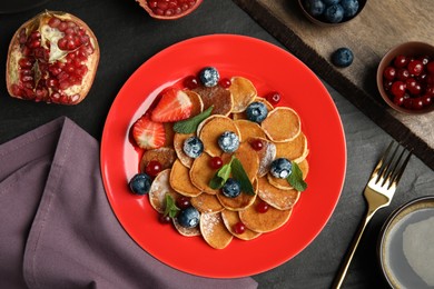 Photo of Cereal pancakes with berries and mint on black table, flat lay