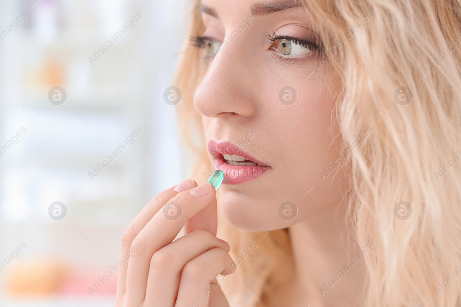 Photo of Young woman taking pill indoors