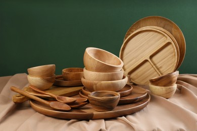 Photo of Set of wooden dishware and utensils on table against green background