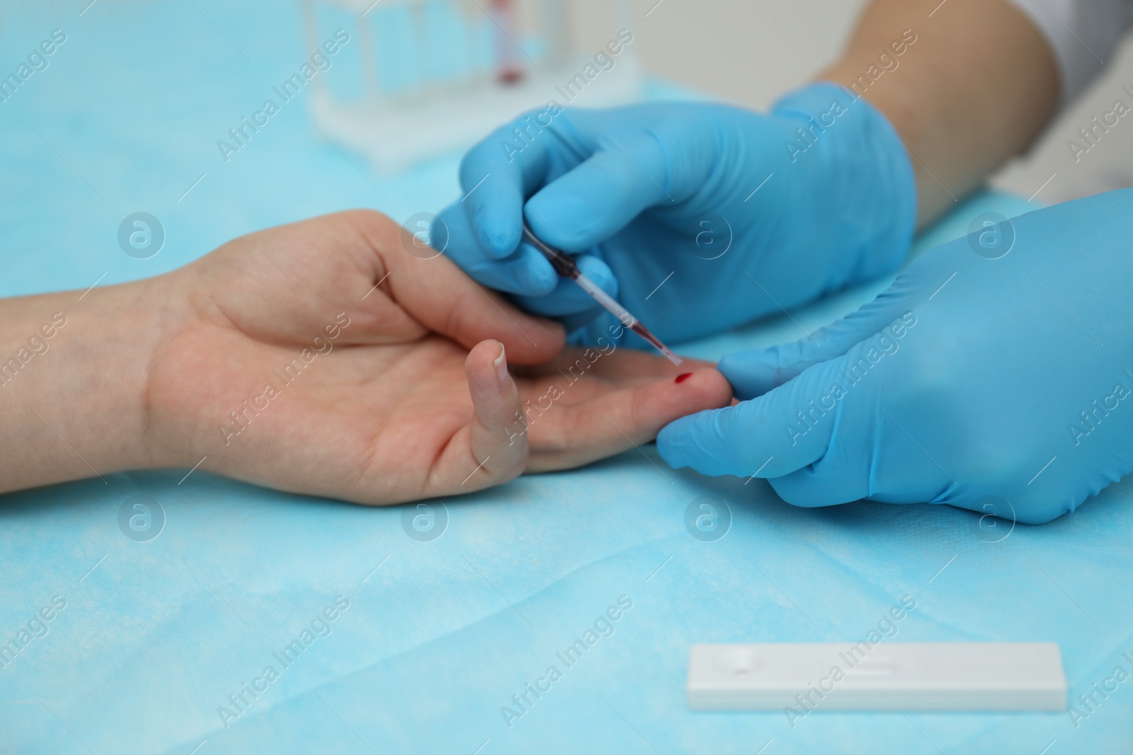 Photo of Doctor taking blood sample from patient's finger at table, closeup