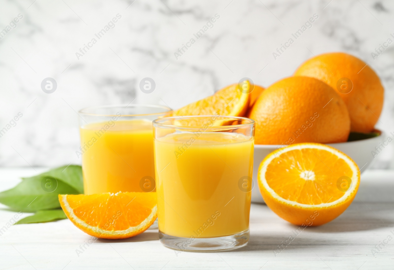 Photo of Glasses of orange juice and fresh fruits on white table