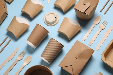 Photo of Eco friendly food packaging. Paper containers and tableware on light blue background, above view