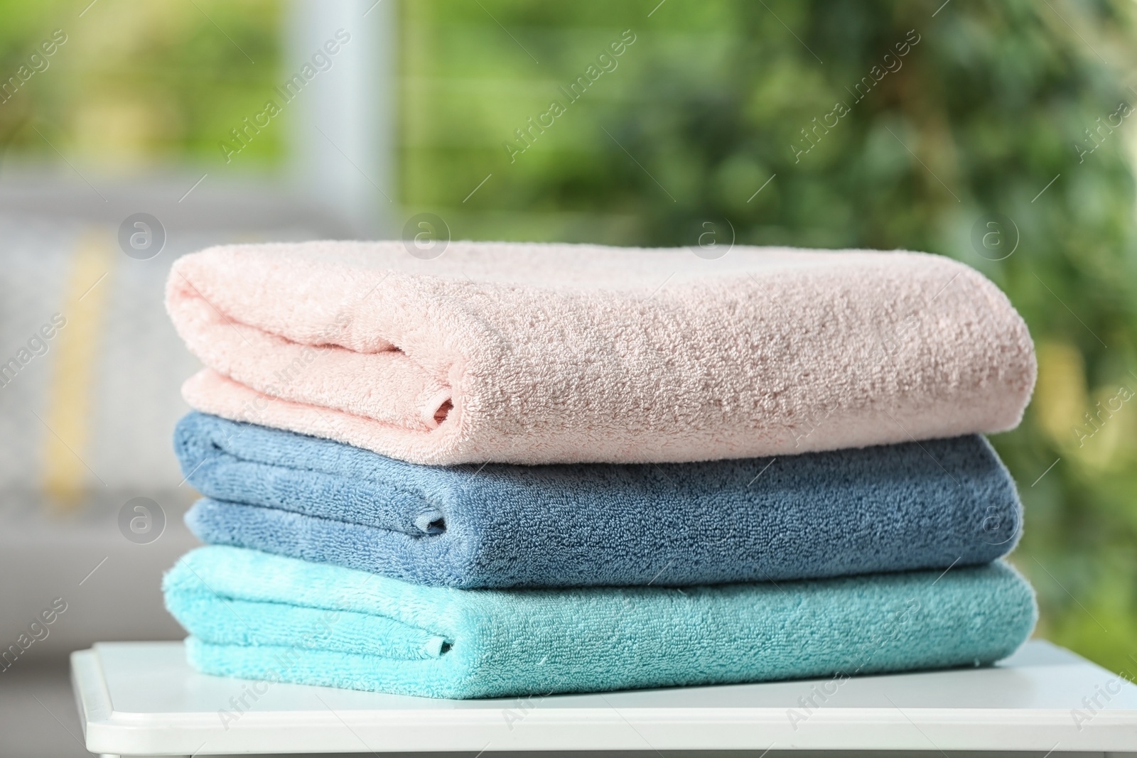 Photo of Stack of folded clean soft towels on table indoors, closeup