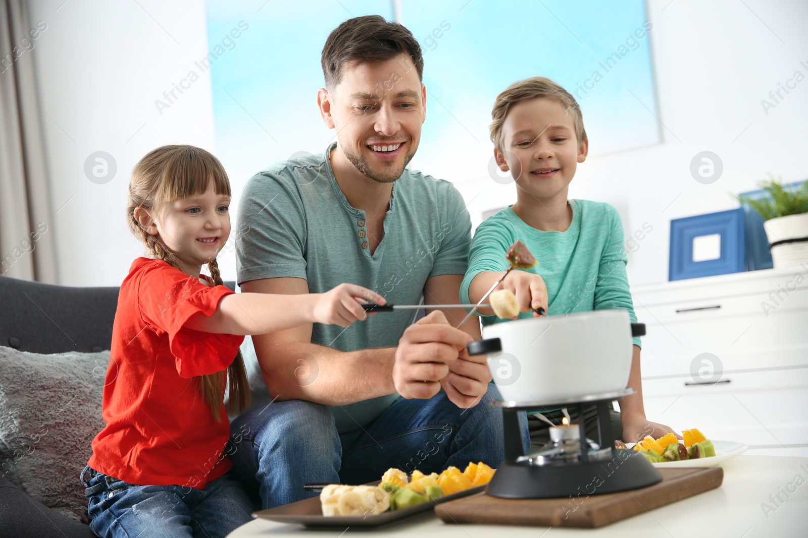 Photo of Children enjoying fondue dinner with father at home