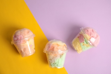 Photo of Yummy cotton candy in plastic cups on color background, top view