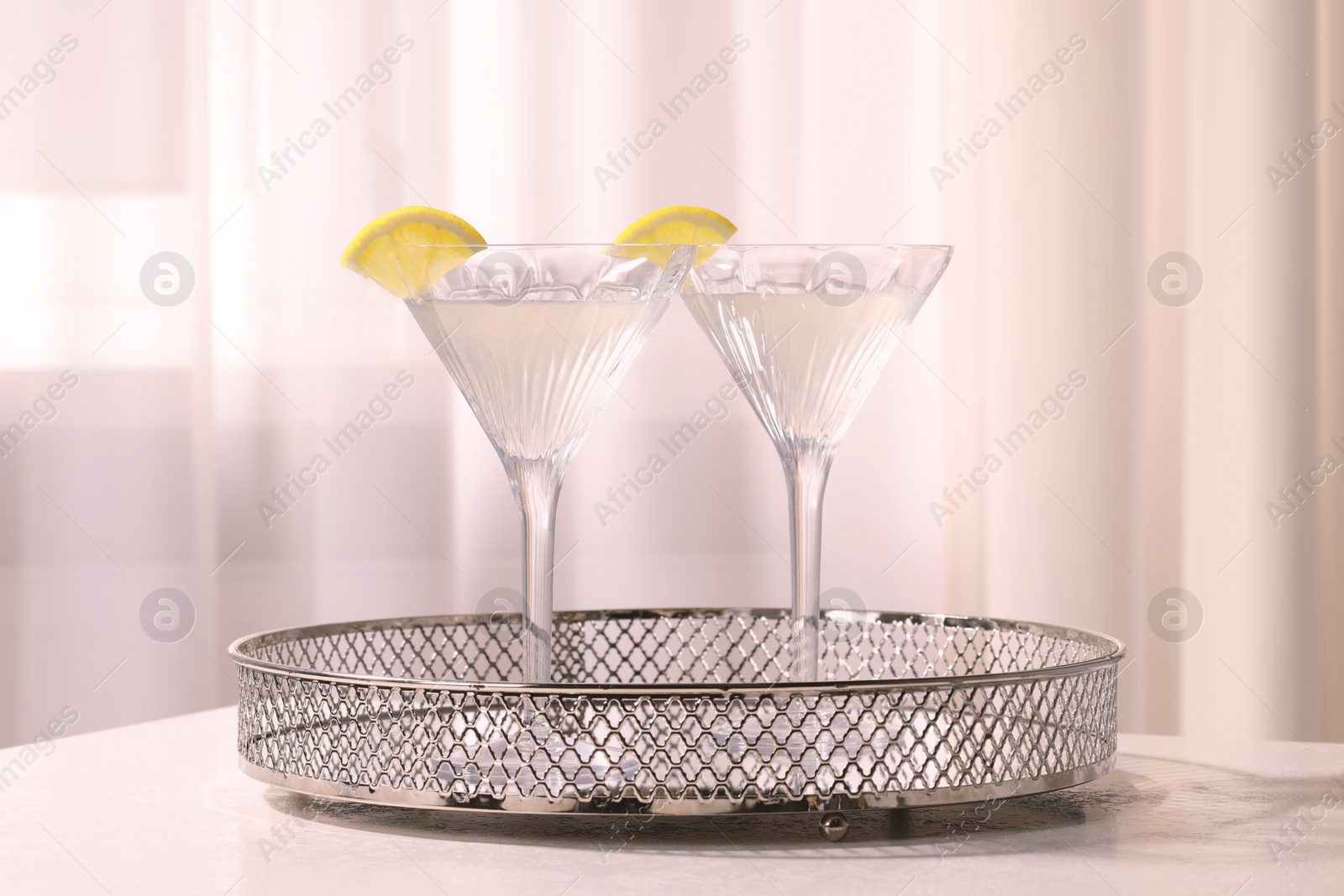 Photo of Tray with martini glasses of fresh cocktail and lemon slices on white table indoors