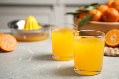 Photo of Glasses of fresh tangerine juice on marble table. Space for text