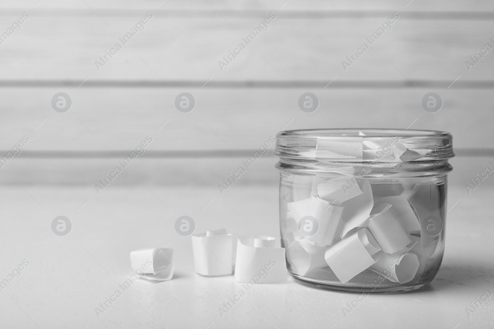 Photo of Glass jar with paper pieces on white table