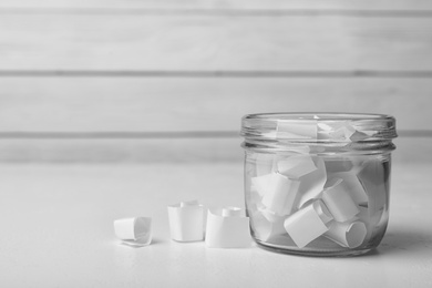 Photo of Glass jar with paper pieces on white table