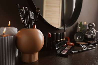 Photo of Stylish round mirror hanging above dressing table with cosmetic products