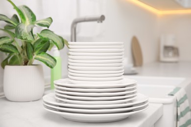Photo of Set of clean dishes and houseplant on table in stylish kitchen