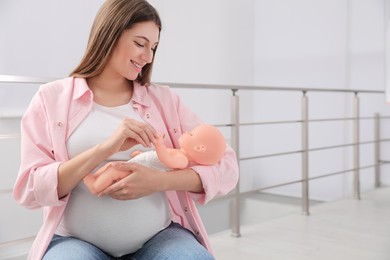 Photo of Pregnant woman with doll at courses for expectant mothers indoors