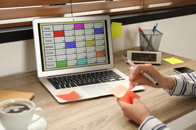 Photo of Young woman using calendar app on laptop in office, closeup