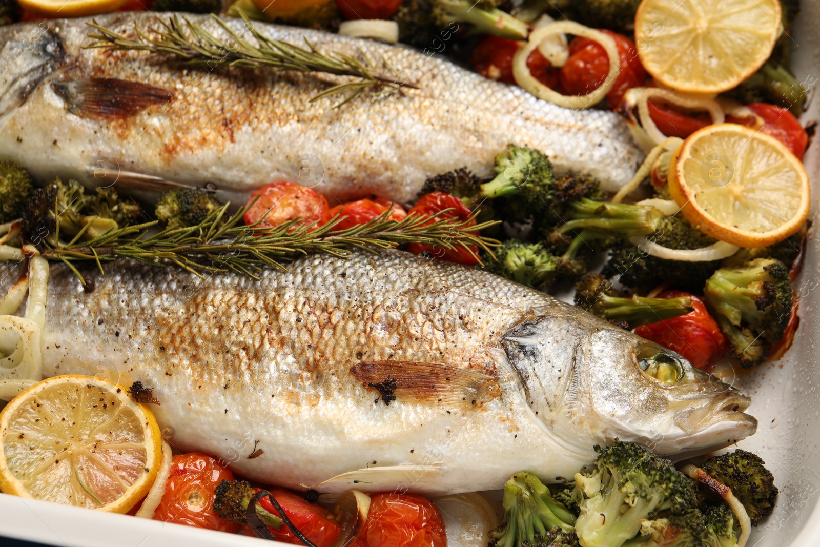 Photo of Delicious fish with vegetables and lemon in baking dish, closeup