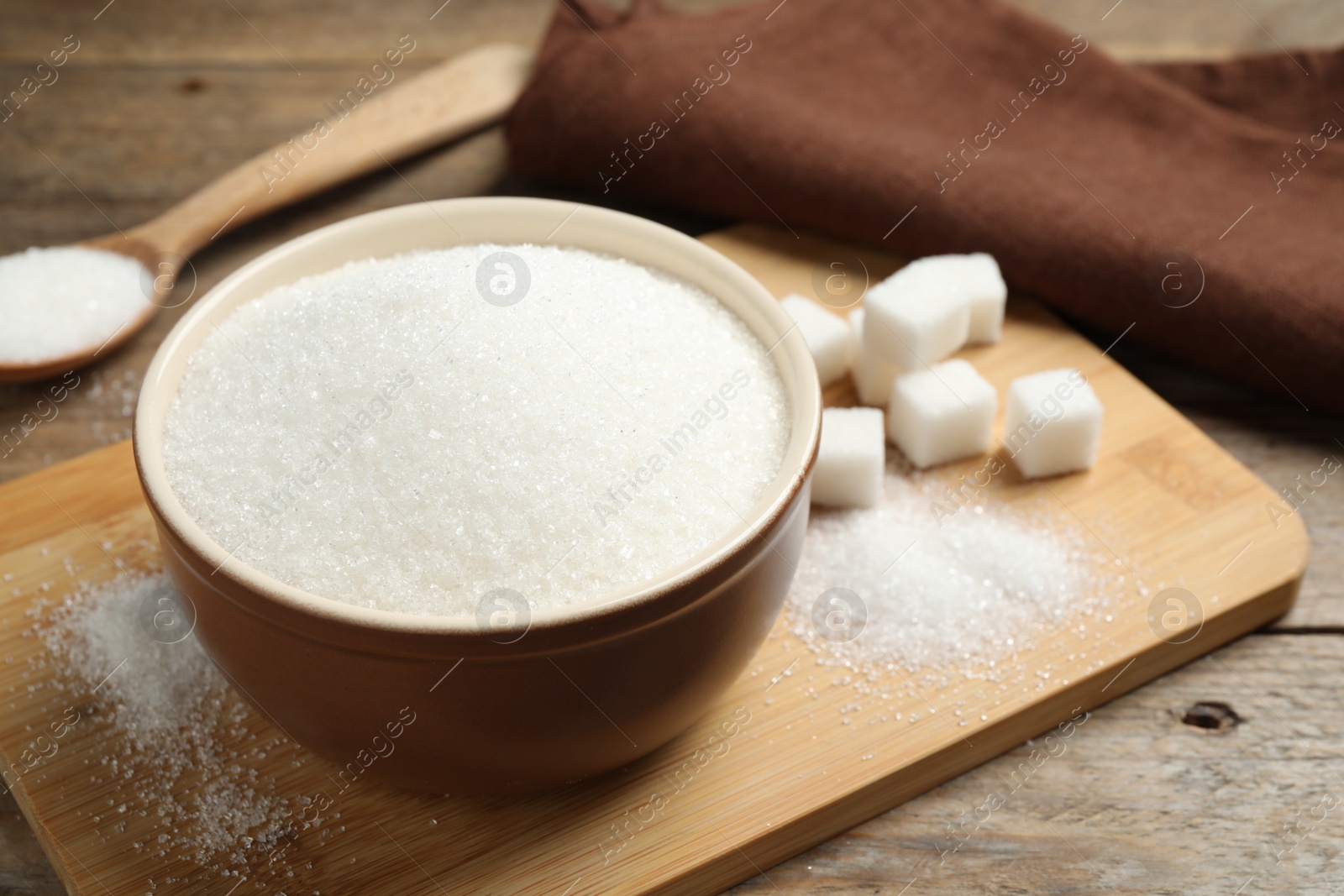 Photo of Granulated sugar in bowl on wooden table