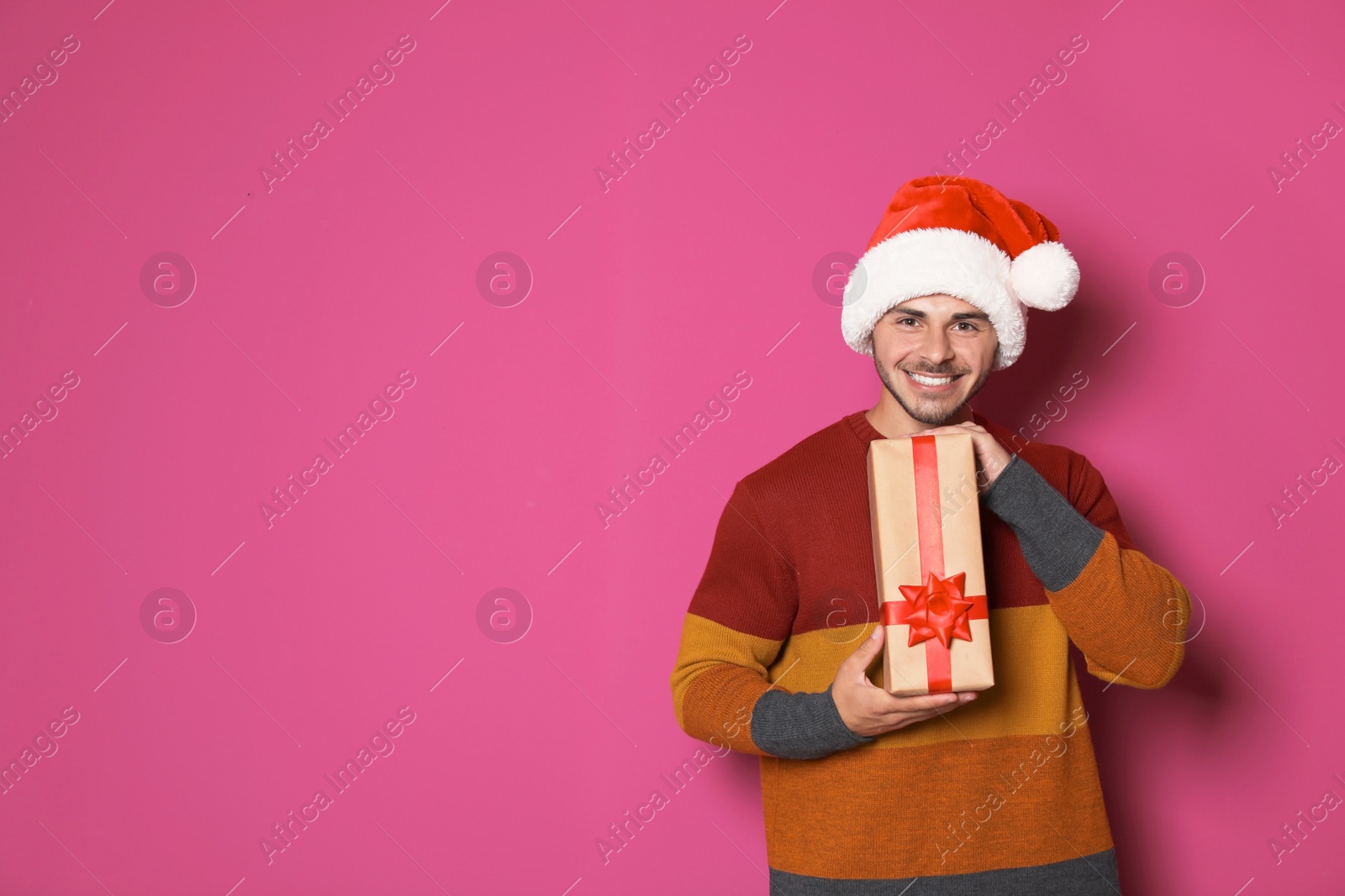 Photo of Young man with Christmas gift on color background