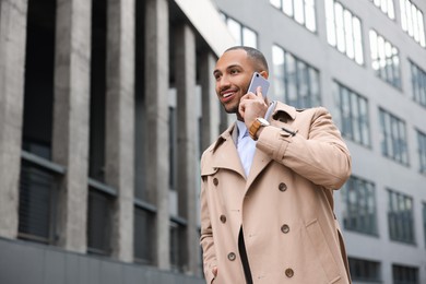 Photo of Happy man talking on smartphone outdoors, space for text. Lawyer, businessman, accountant or manager