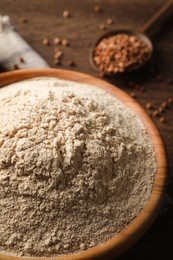 Photo of Bowl of buckwheat flour on wooden table, closeup