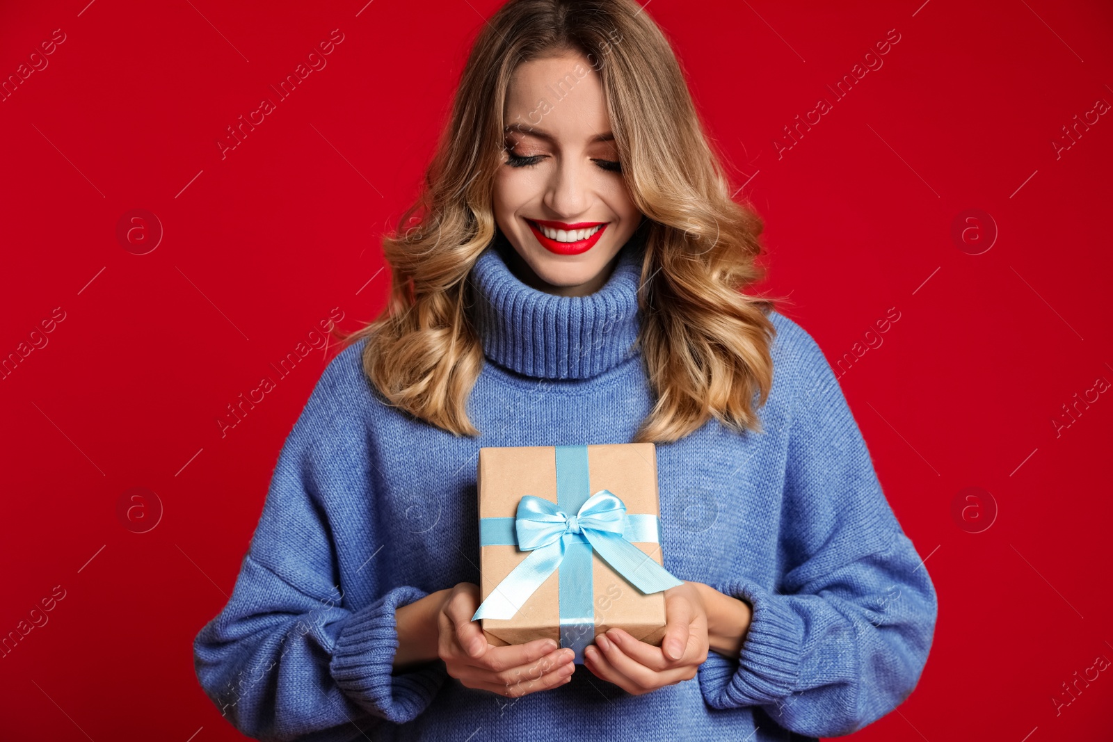Photo of Happy young woman with Christmas gift on red background