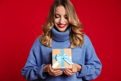 Photo of Happy young woman with Christmas gift on red background