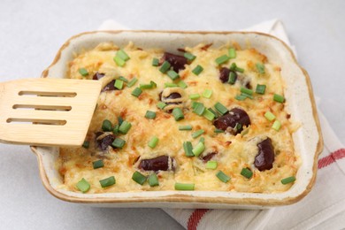 Photo of Tasty sausage casserole with green onions in baking dish on white table, closeup