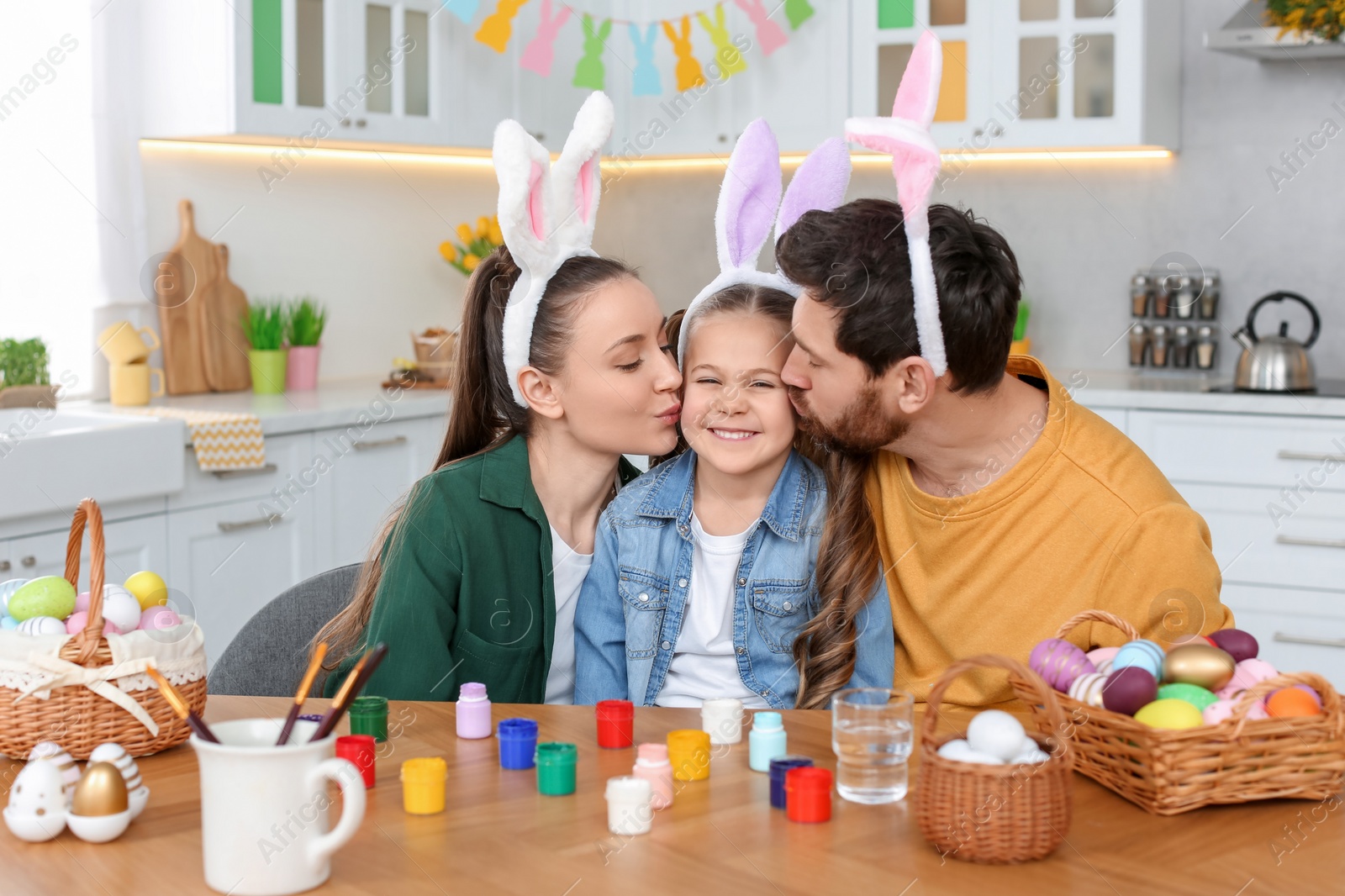 Photo of Happy family with Easter eggs at table in kitchen