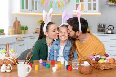 Photo of Happy family with Easter eggs at table in kitchen