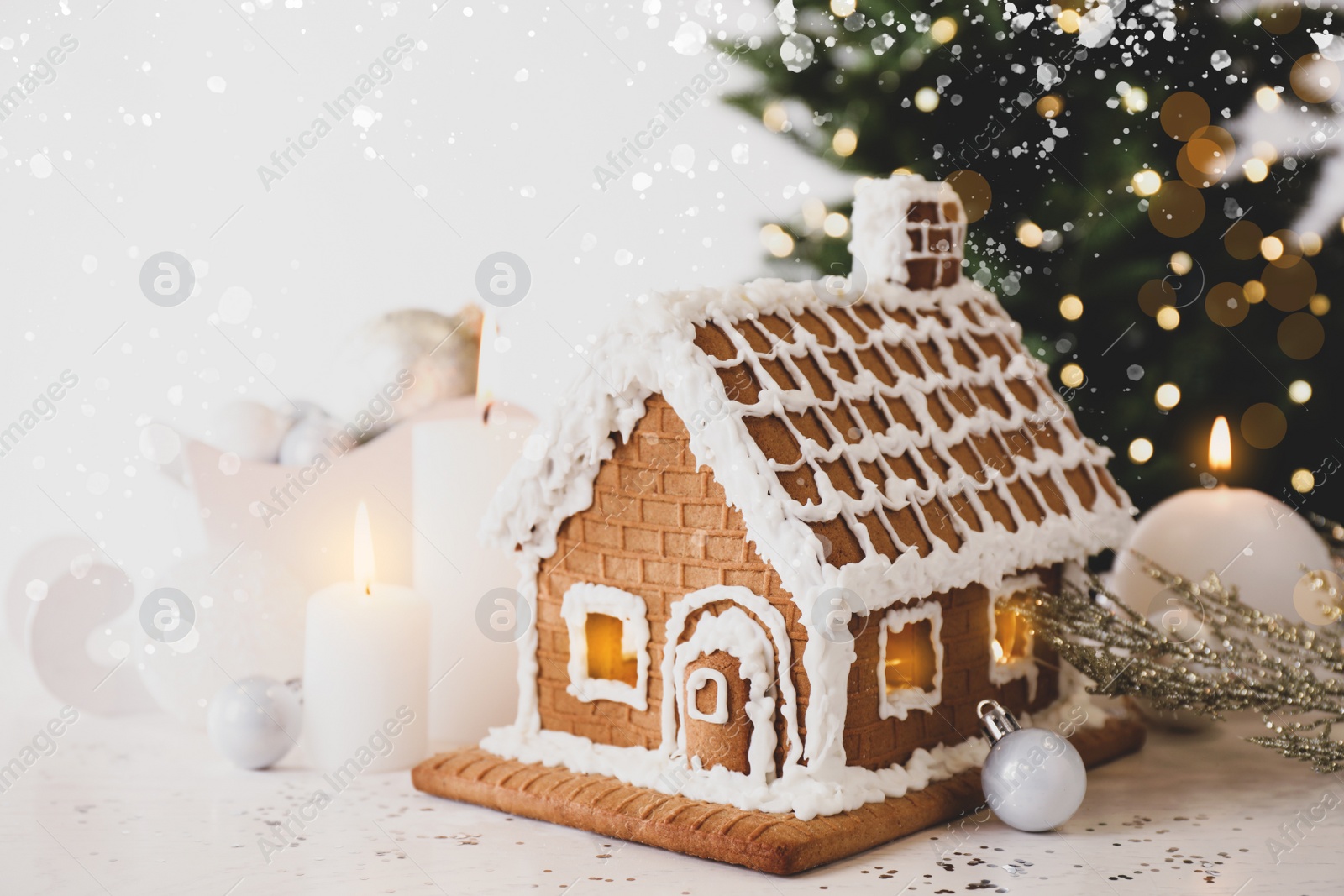 Image of Beautiful gingerbread house decorated with icing and candles on white table