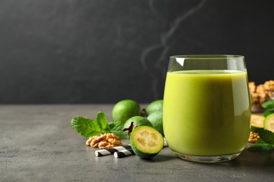 Photo of Fresh feijoa smoothie in glass on grey table, space for text