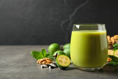 Fresh feijoa smoothie in glass on grey table, space for text