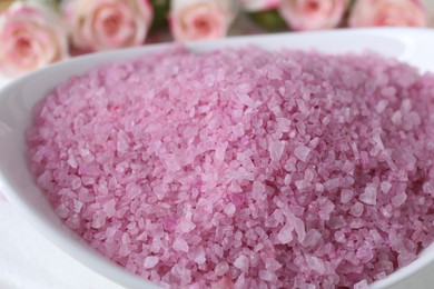 Bowl with pink sea salt on blurred background, closeup